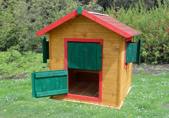 dřevěný zahradní domek pro děti v medovém odstínu s barevnými dveřmi a okenicemi se šindelovou střechou a povrchovým nátěrem lazurit